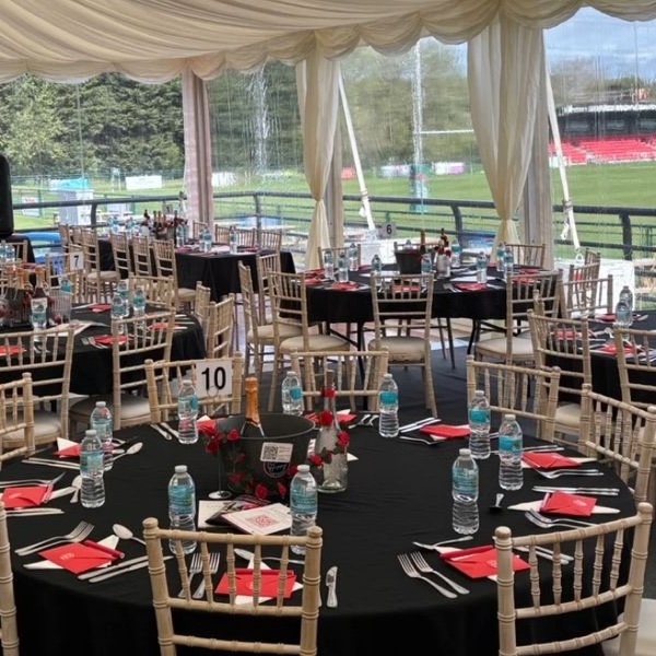 Table 10 set with champagne on ice, red roses, red napkins and limewash chiavari chairs